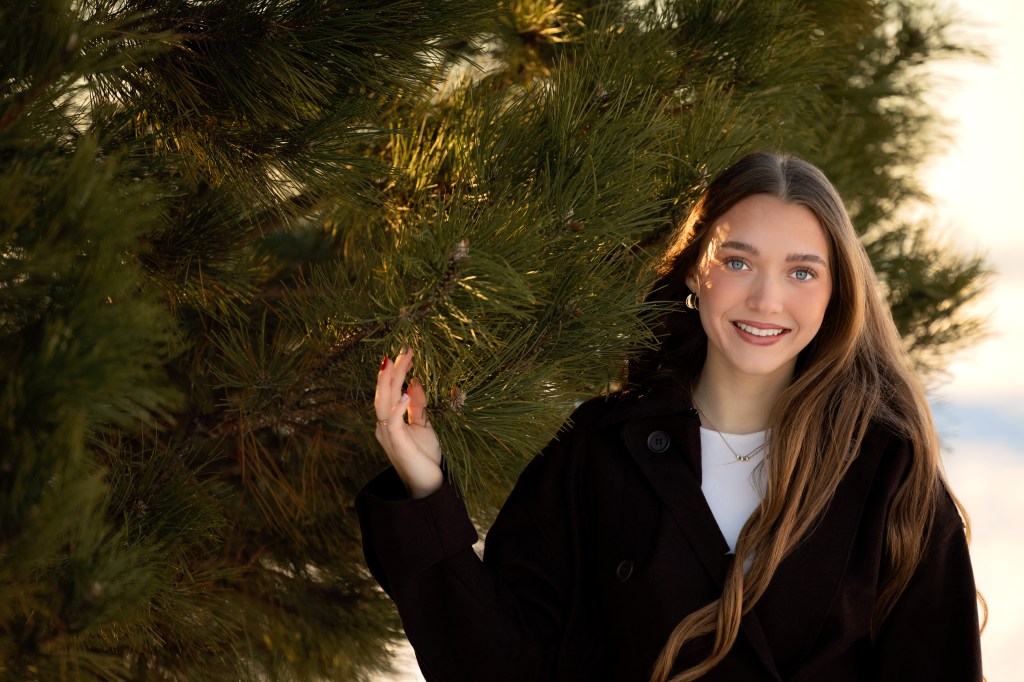 Senior portrait of Callie at Silver Beach in St. Joseph, Michigan with Lake Michigan and the lighthouse visible on a clear winter afternoon.