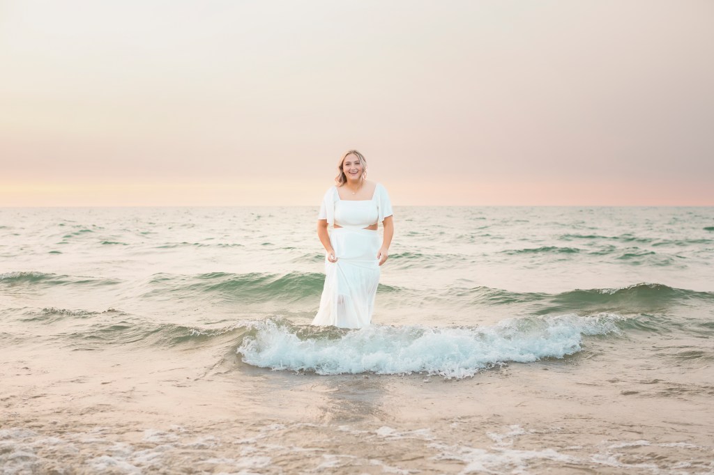 Senior posing in lake michigan waves in St. Joseph, MI