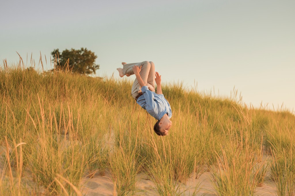 senior doing a backflip on lake michigan shoreline senior portraits