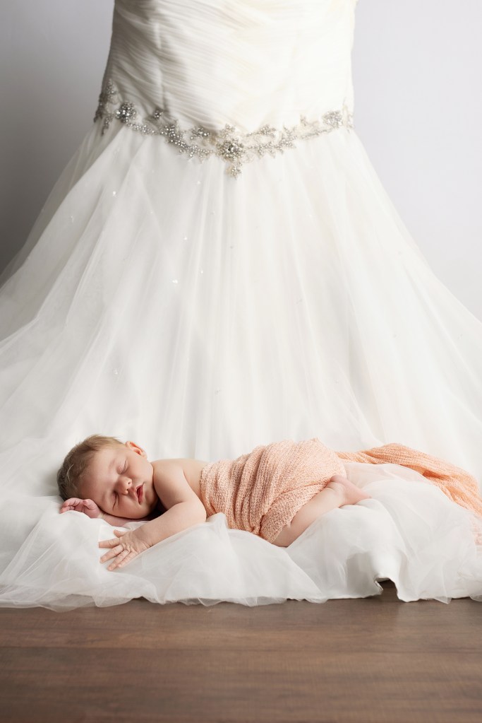 newborn posed on mom's wedding dress