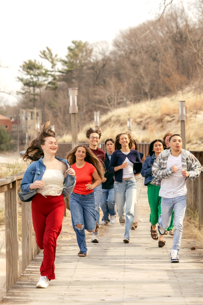 High school seniors running down the beach boardwalk during a Southwest Michigan senior photo session