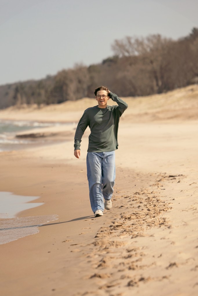 Senior portrait of a boy walking near Lake Michigan sand dunes during a Bridgman beach session