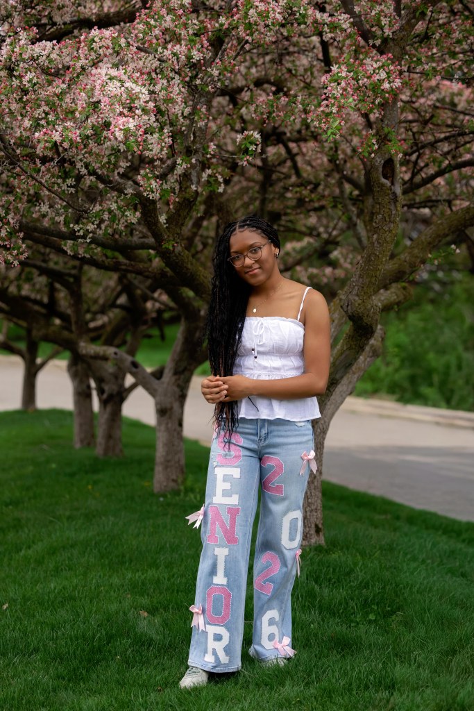 Senior girl wearing senior custom jeans under trees in St. Joseph michigan