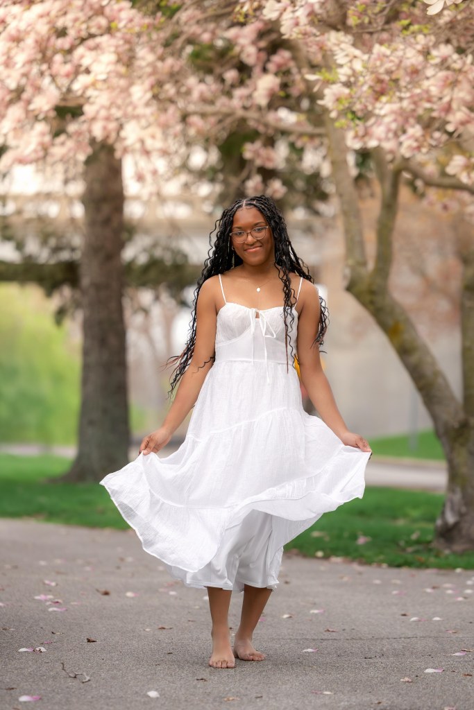 Senio girl in white dress posing under flowering trees in south west michigan