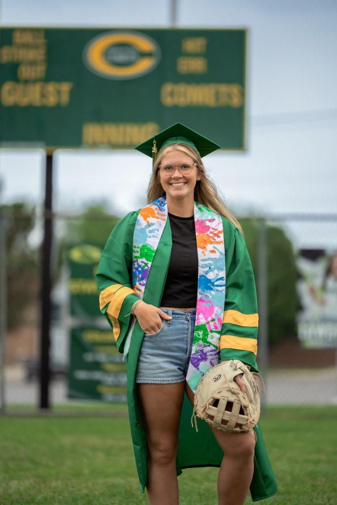 Coloma High School softball player celebrating graduation with cap and gown photos on the field