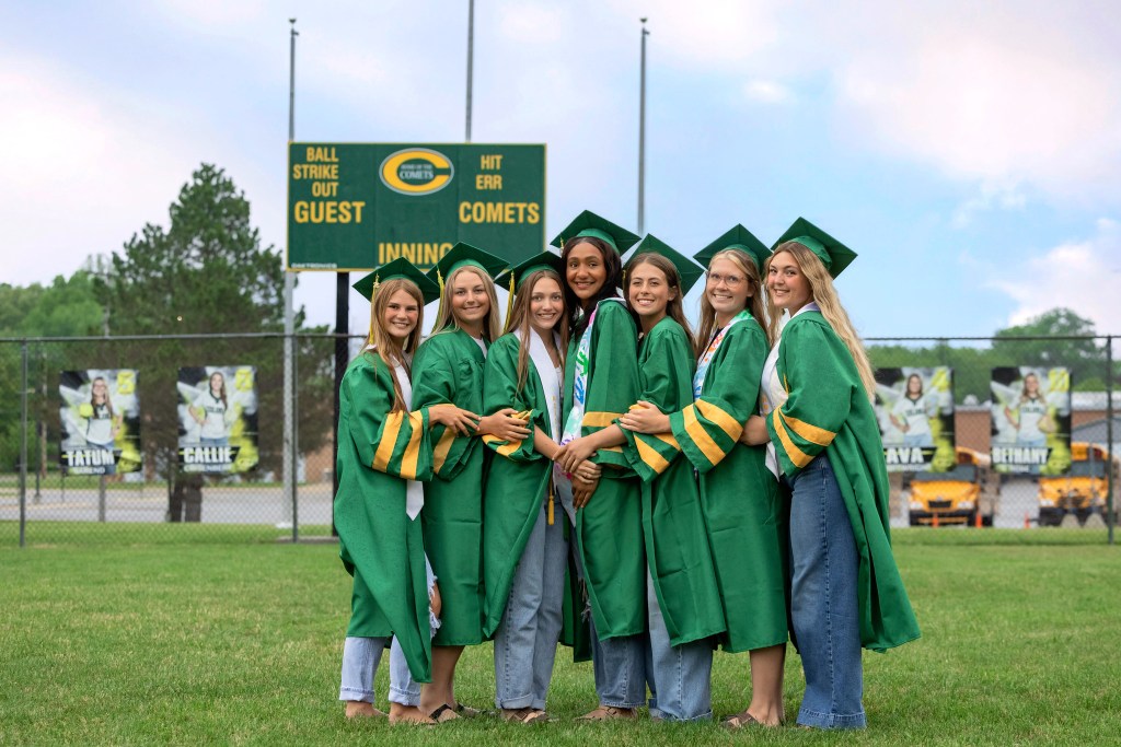 Coloma Varsity Softball seniors posing in caps and gowns on softball field