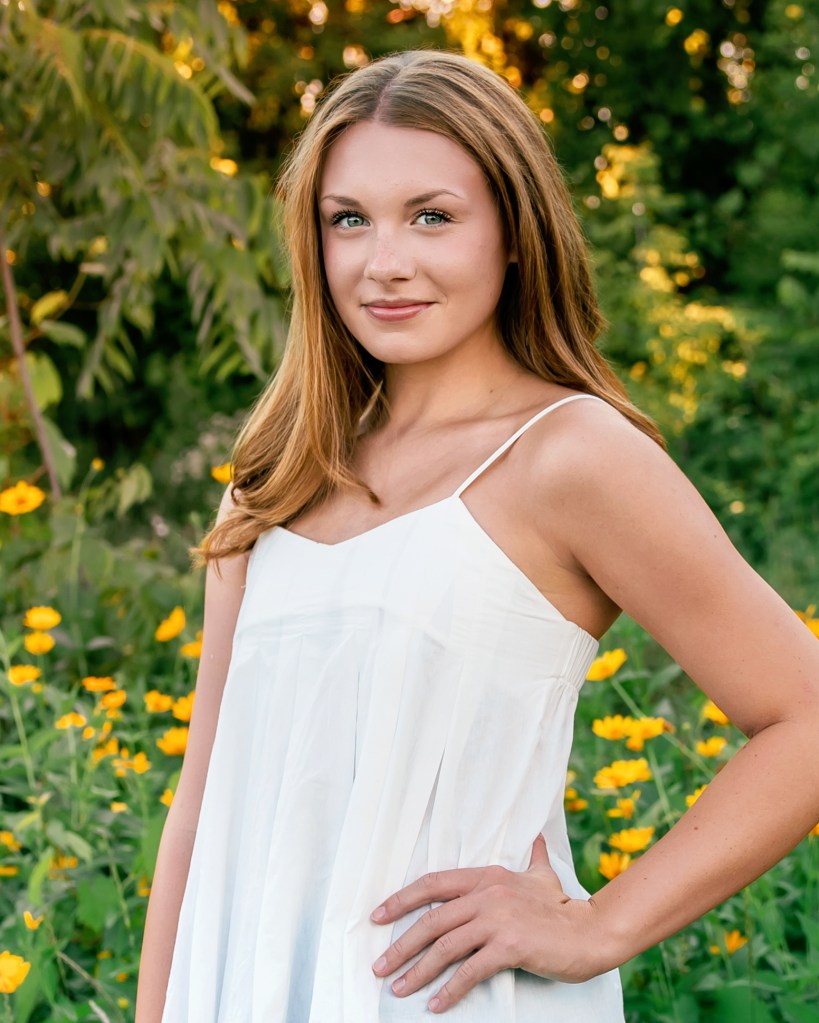 St. Joseph High School senior Emma surrounded by colorful summer wildflowers during her Class of 2027 senior portraits.