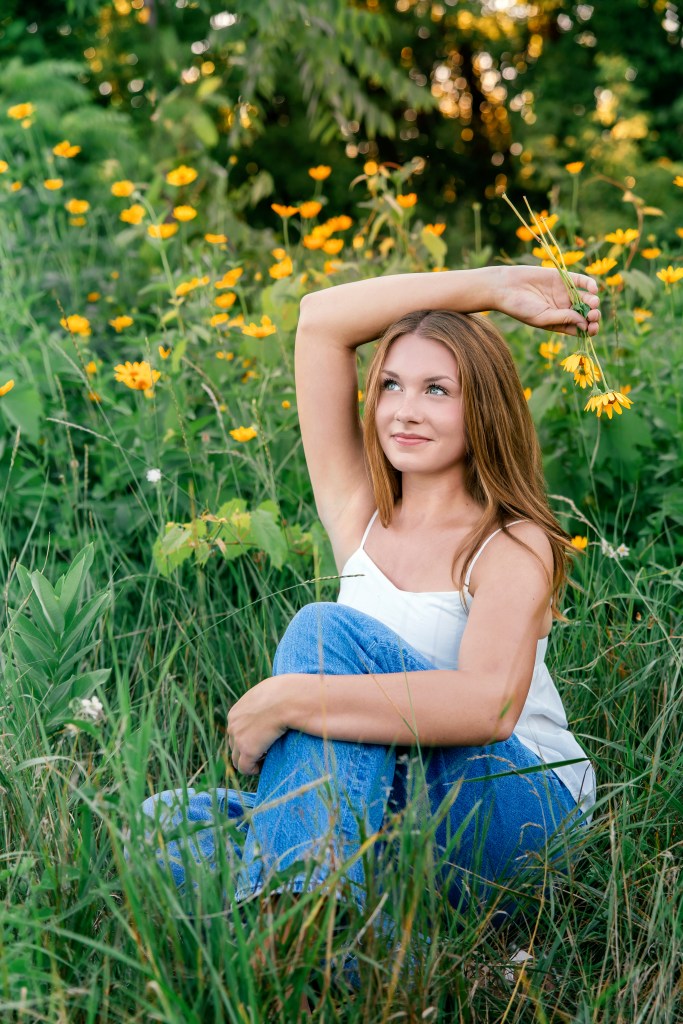 St. Joseph High School Class of 2027 senior Emma standing among blooming wildflowers during her summer senior pictures in Southwest Michigan.