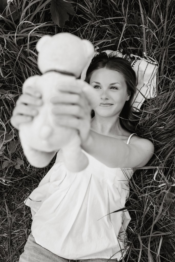 Close-up portrait of St. Joseph High School senior Emma with her childhood stuffed bear in a Michigan wildflower meadow.