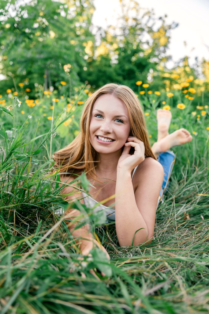 St. Joseph High School senior Emma laying in a colorful wildflower field during her Class of 2027 senior pictures in Southwest Michigan.
