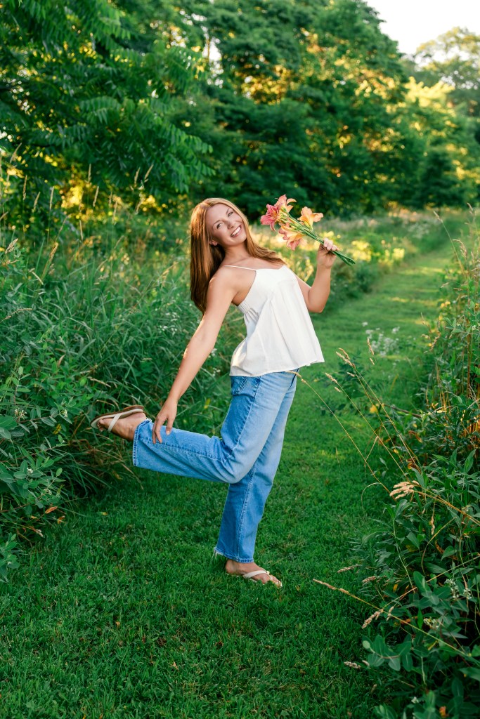 Emma laughing as she walks through a blooming Southwest Michigan wildflower field during her St. Joseph High School senior session.