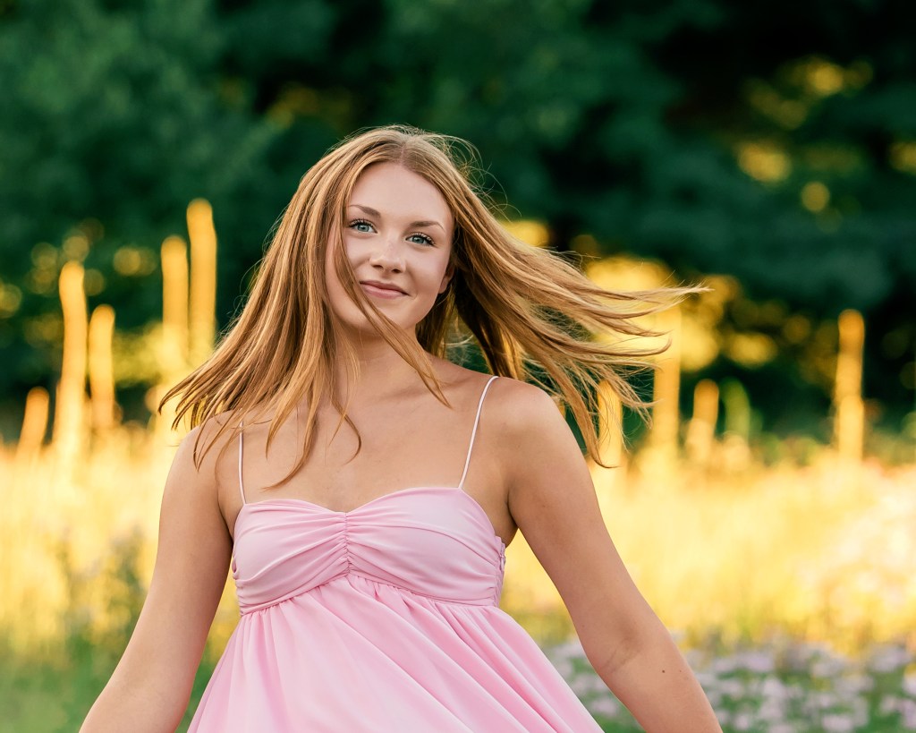 Portrait of Emma in a blush pink dress among native Michigan wildflowers during her Southwest Michigan senior photo session.