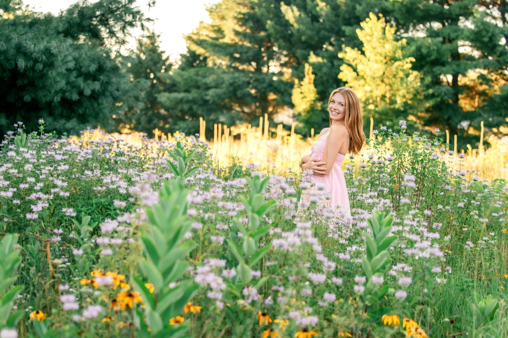 Emma, St. Joseph High School Class of 2027 senior, smiling among yellow wildflowers during her Southwest Michigan senior session.