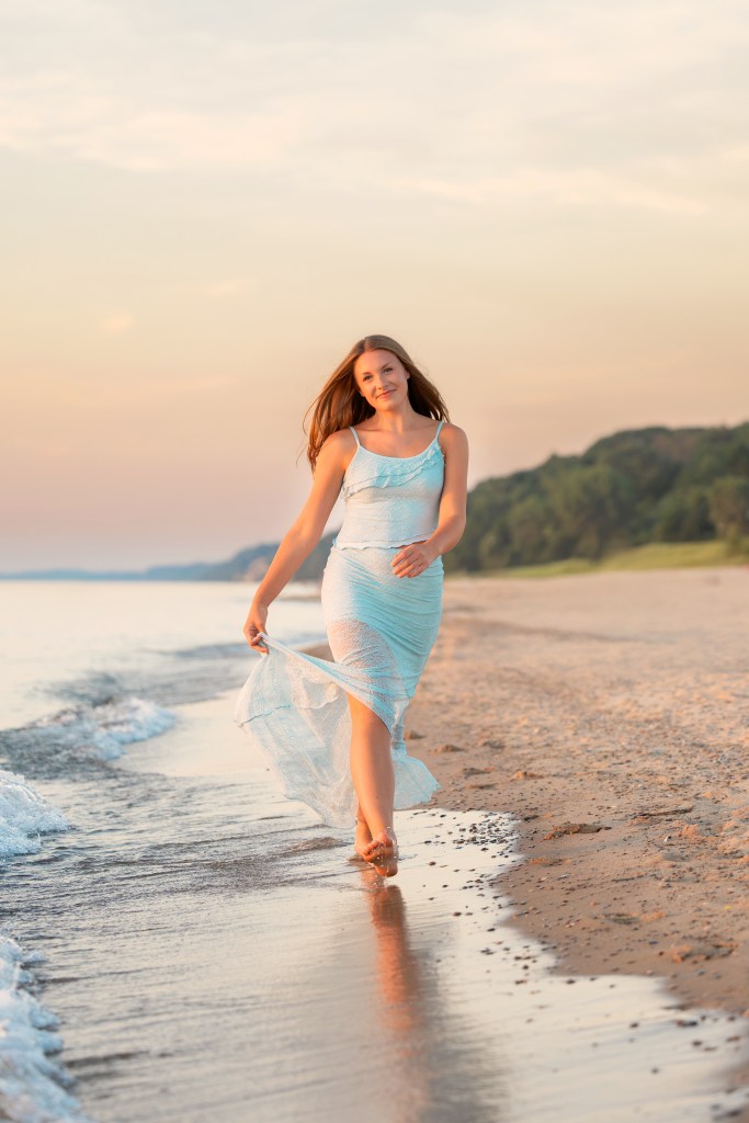 St. Joseph High School senior Emma walking along the Lake Michigan shoreline at Jean Klock Beach during her Class of 2027 senior session.