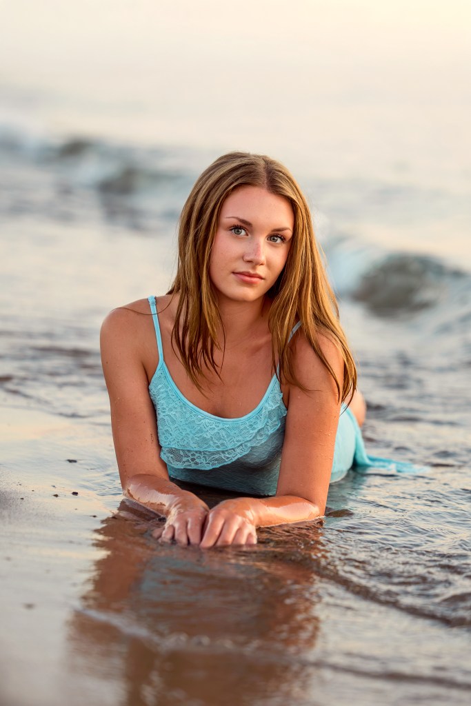 Emma in the water as gentle waves roll onto the shore at Jean Klock Beach during her Southwest Michigan senior portraits.