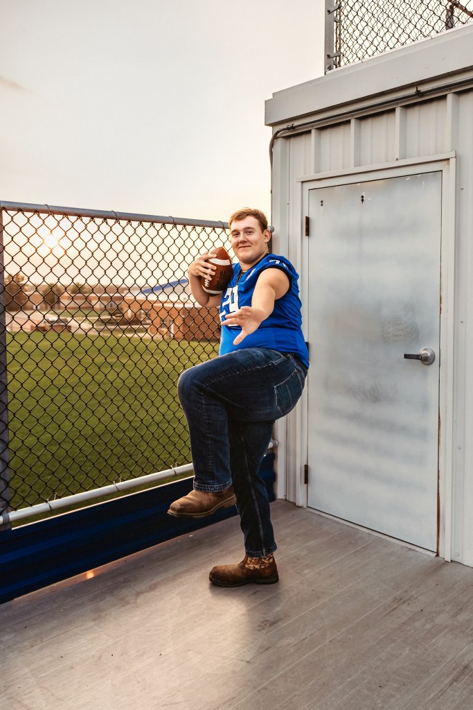 Lawton High School Class of 2027 senior standing with a football beside the stadium entrance at Lawton High School.