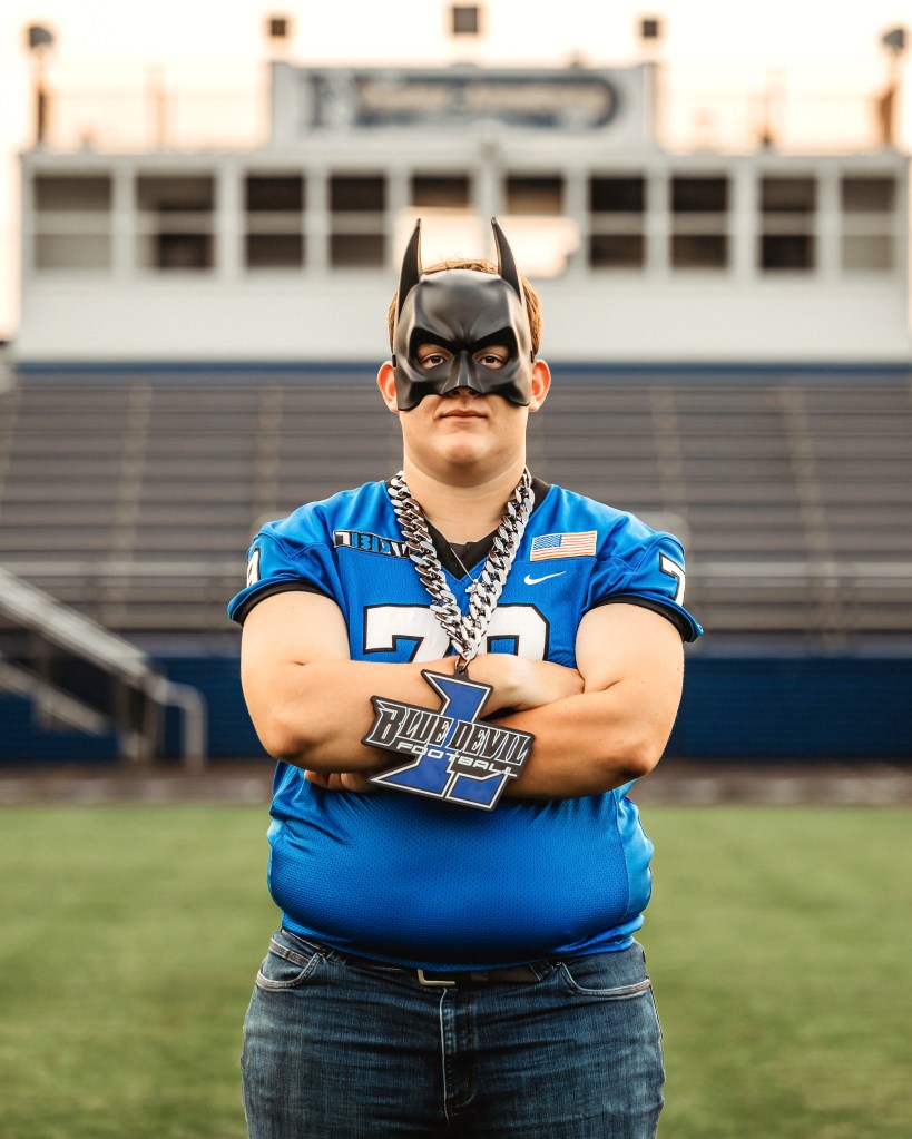 Lawton High School Class of 2027 football player wearing a Batman mask on the football field during senior pictures.