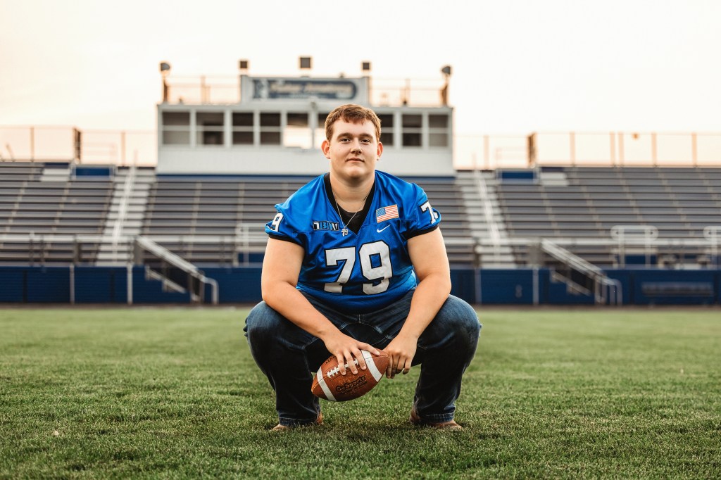 Lawton High School Class of 2027 senior crouching on the football field at Lawton High School during sunset.