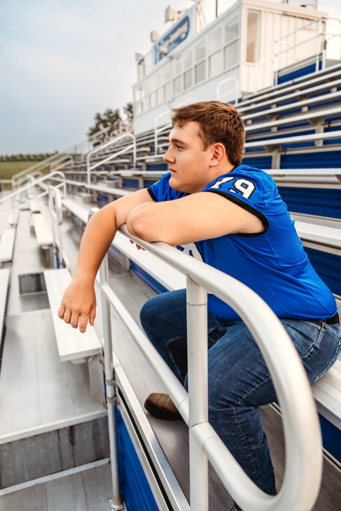 Lawton High School Class of 2027 senior leaning on the football stadium railing during golden hour.