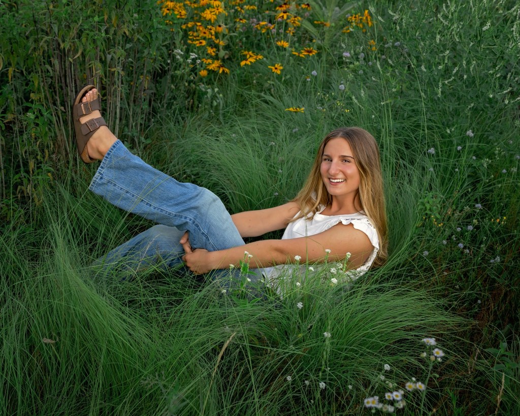 High school senior sitting in a blooming wildflower meadow during a Southwest Michigan senior portrait session.