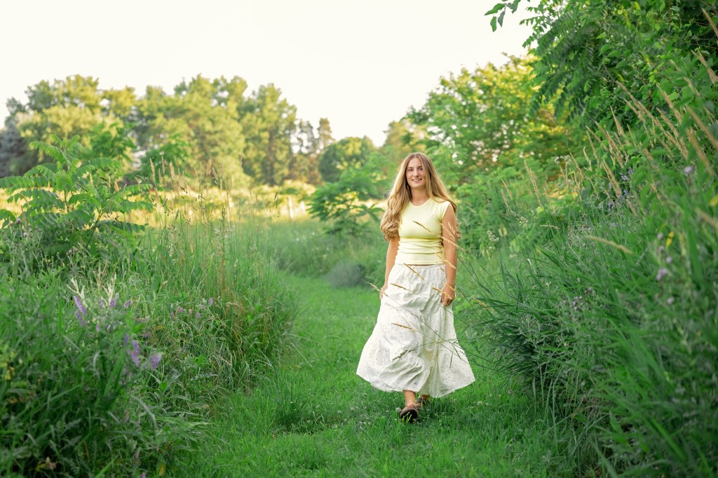 Class of 2027 senior walking along a grassy path through a private wildflower field near Benton Harbor, Michigan.

