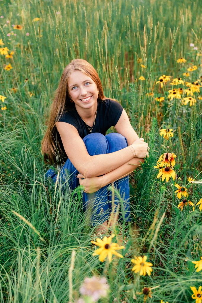 Hadley smiling wearing a black shirt posing in the wildflowers