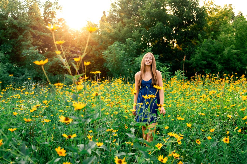 High school senior from michigan posing in wildflower fiel in golden light