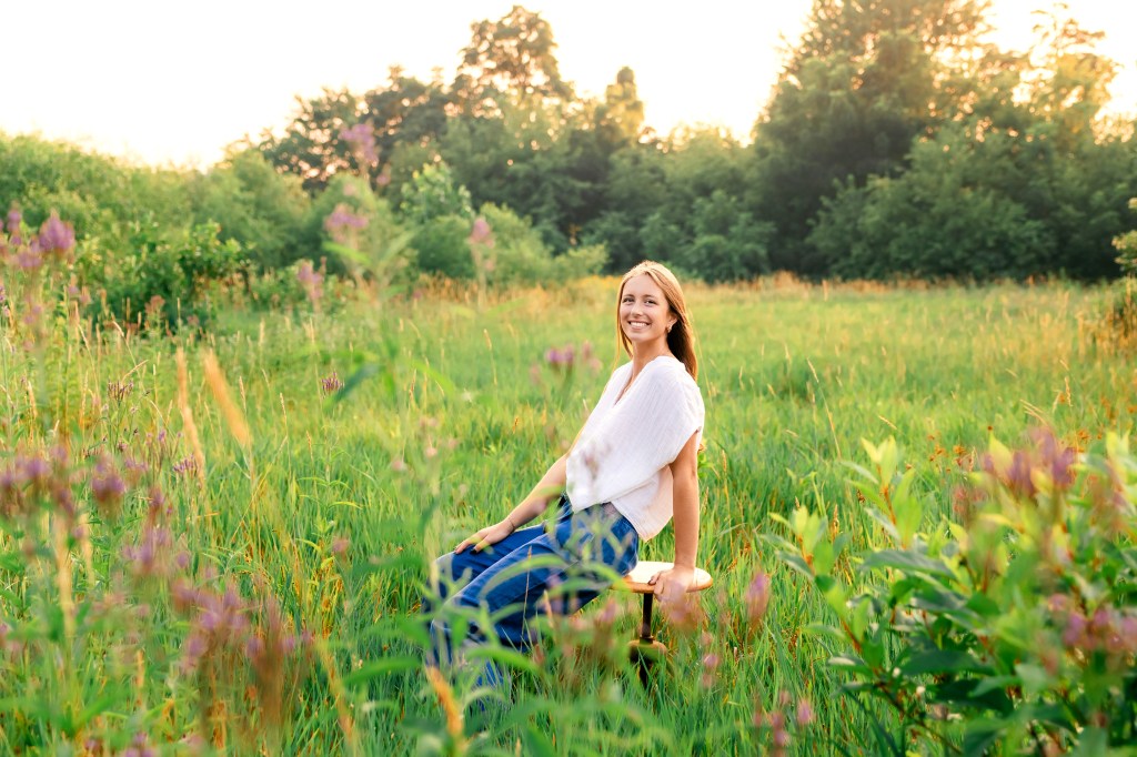 high school girl class of 2027 posing seated in a wildflower meadow in southwest michigan